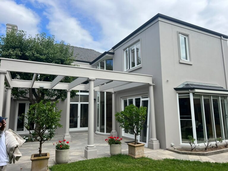 Kew backyard exterior painting with light grey rendered walls, white pergola columns and patio