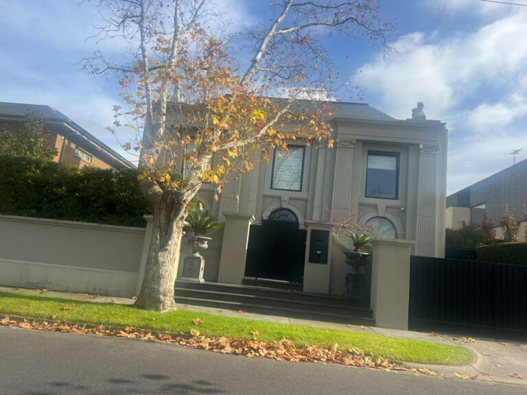 Two-storey Kew house exterior painting in beige with black window frames, gates and landscaped front lawn