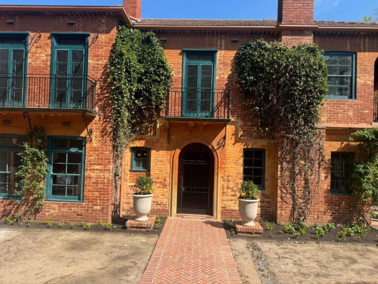 Toorak heritage brick house with freshly painted teal window frames, balcony doors and dark ironwork