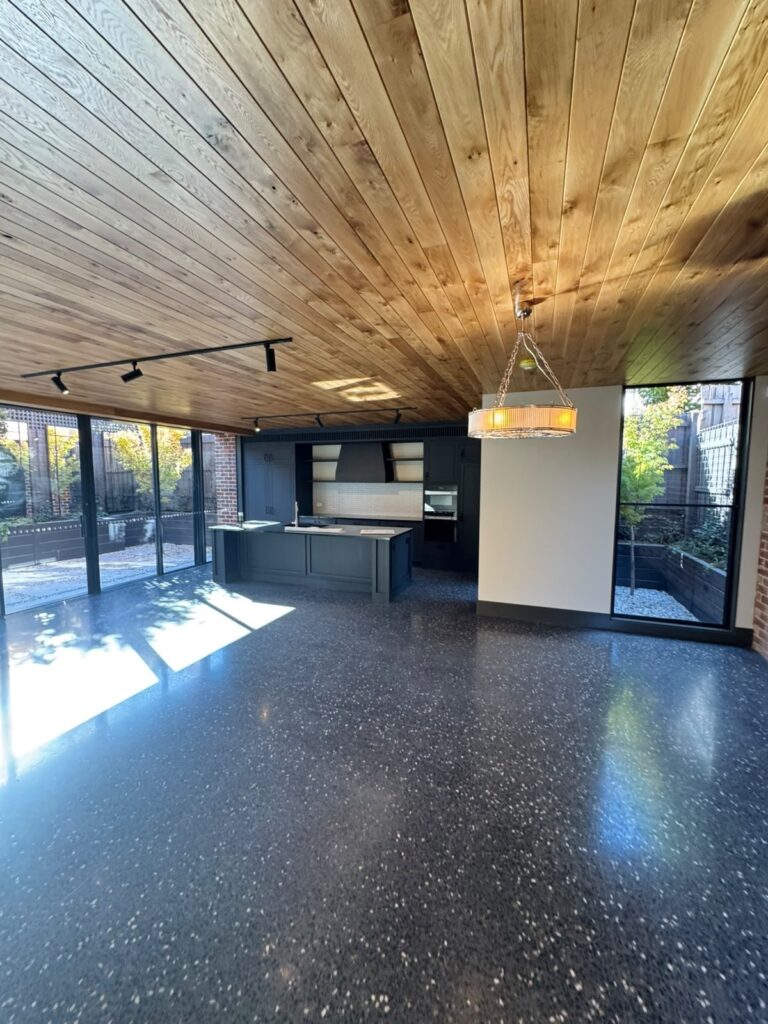 Toorak open-plan kitchen interior with white painted walls, charcoal cabinetry and a timber ceiling