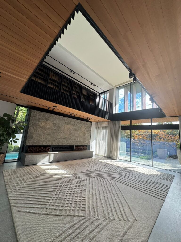 Toorak double-height living room interior painting with white walls, wood ceiling and stone fireplace wall
