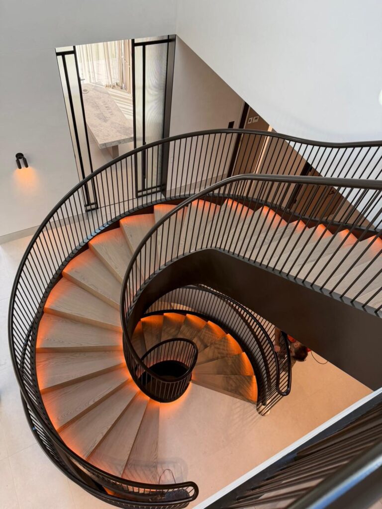 Spiral staircase in a Toorak home with white interior walls, timber treads and black painted stringers
