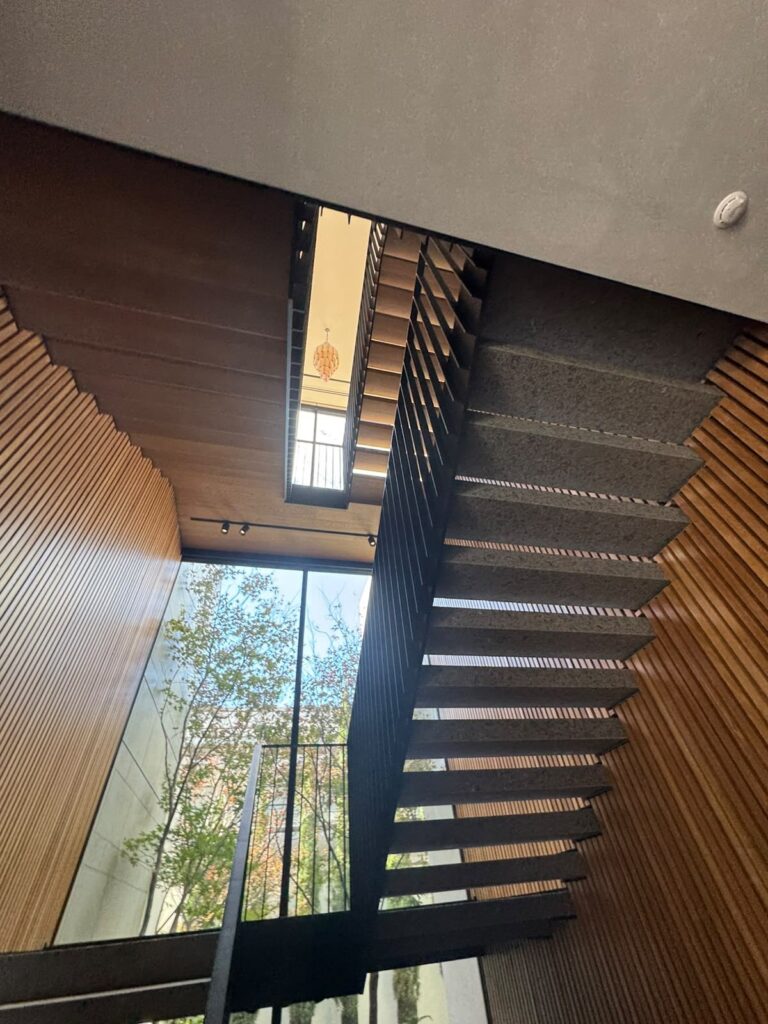 Multi-level Toorak stairwell with painted grey walls, timber slats and a large window